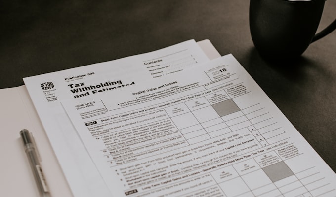 Factory accountant reviewing accounts receivable aging report on laptop with invoices on desk